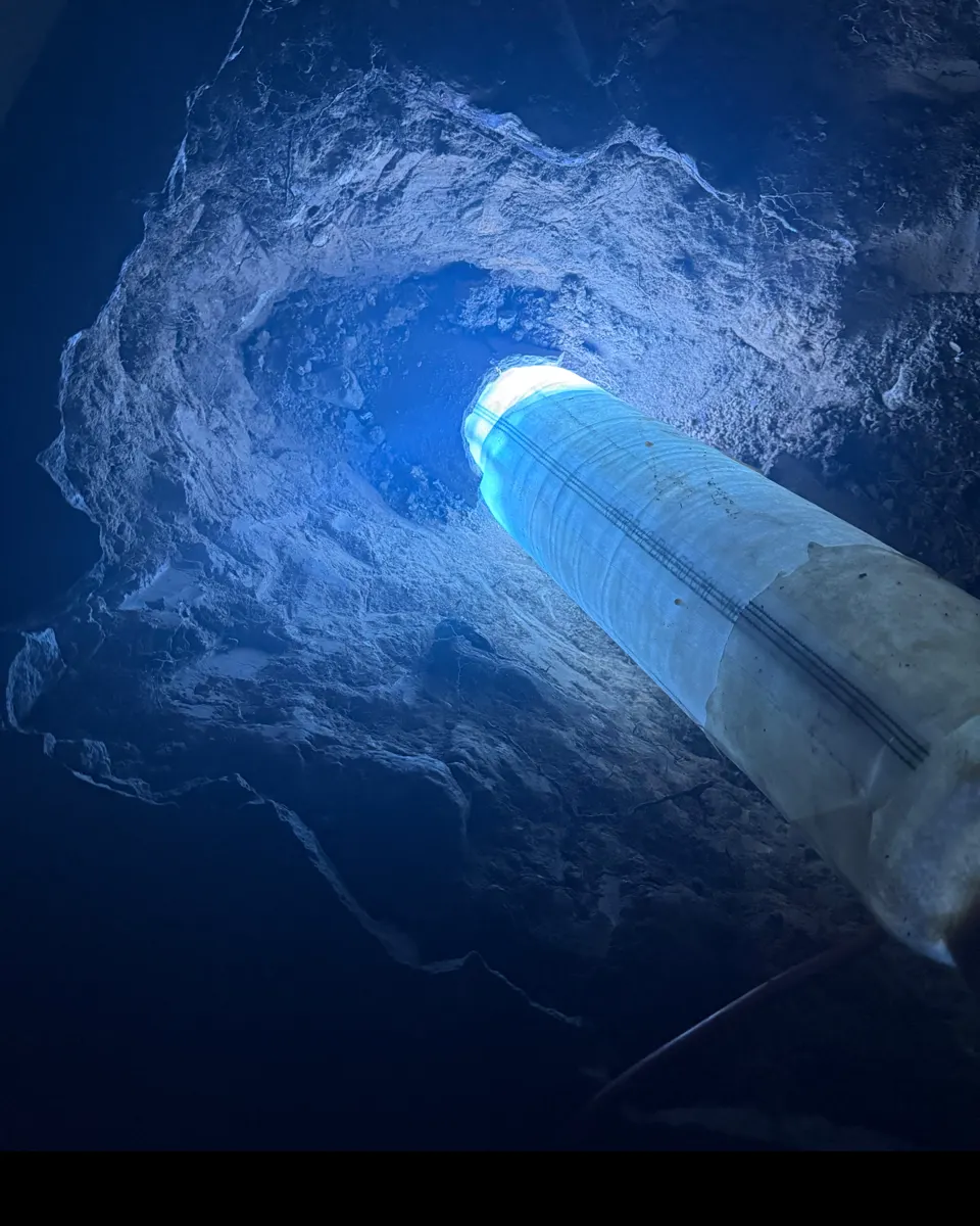 Blue work light shining on a pipe in an open excavation